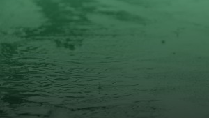 Una imagen de cerca del agua de lluvia cayendo sobre el pavimento.